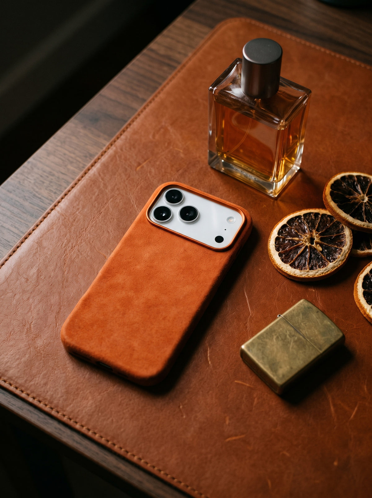 Orange Velluto Case next to a perfume bottle on leather